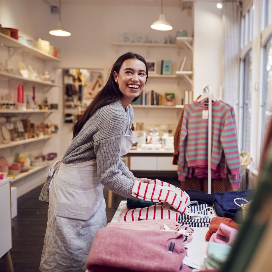 Female small business owner arranges stock in window display