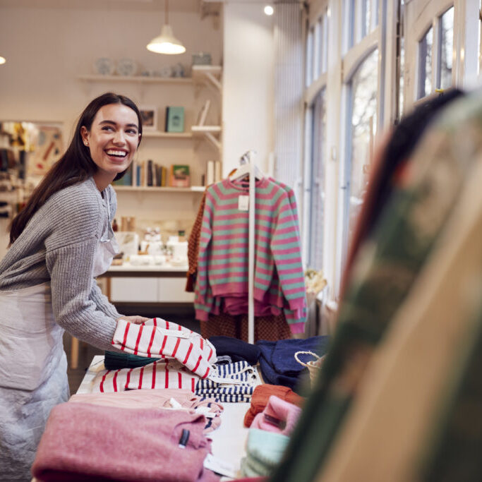 Female Small Business Owner Arranges Stock In Window Display